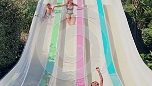 Kids and adult have fun on colorful slides in summer waterpark