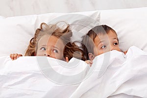 Kids afraid pulling the quilt on their heads photo