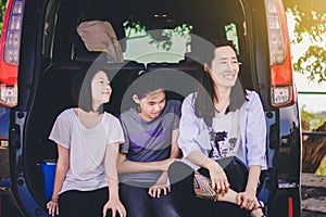 Kids and Auntie relax on car after long trip