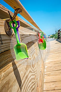 Kids beach toys hanging on boardwalk entrance to the beach