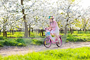 Kids on bike in spring park. Girl riding bicycle