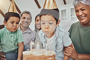 Kids, birthday cake and kid blowing candles at a house at a party with food and celebration. Children, celebrate event