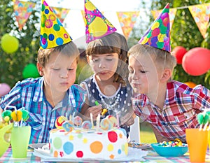 Kids at birthday party blowing candles on cake