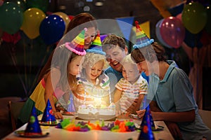 Kids birthday party. Child blowing candles on cake and opening presents on celebration