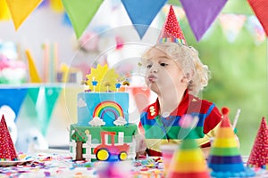 Kids birthday party. Child blowing out cake candle