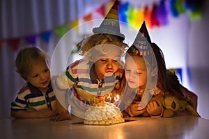 Kids birthday party. Children blow cake candles.