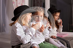 Kids in black hats drink milk.