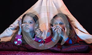 Kids in blanket tent wearing red jammies on black background