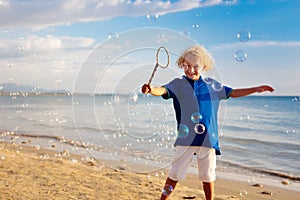 Kids blow bubble at beach. Child with bubbles