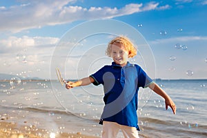 Kids blow bubble at beach. Child with bubbles