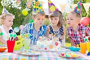 Kids blowing candles on cake at birthday party