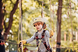 Kids boy adventure and travel. Cute school child boy enjoying a sunny day in a climbing adventure activity park. Cargo