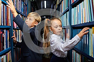 kids boy and girl choose books in library for school
