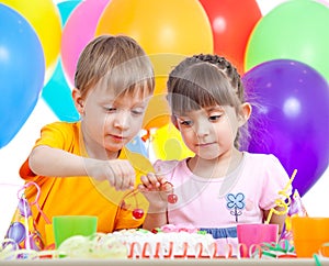 Kids boy and girl eating cake on party birthday