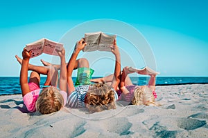 Kids -boy and girls- reading books at beach vacation