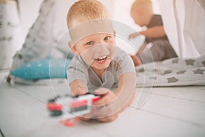 Kids brothers are laying on the floor. Boys are playing in home with toy cars at home in the morning. Casual lifestyle