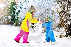 Kids building snowman. Children in snow. Winter fun.