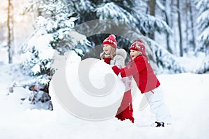 Kids building snowman. Children in snow. Winter fun.