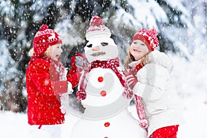 Kids building snowman. Children in snow. Winter fun.