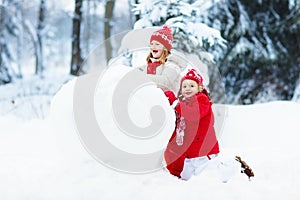 Kids building snowman. Children in snow. Winter fun.