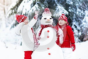 Kids building snowman. Children in snow. Winter fun.