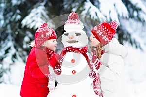 Kids building snowman. Children in snow. Winter fun.