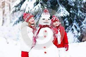 Kids building snowman. Children in snow. Winter fun.