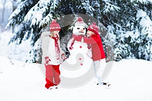 Kids building snowman. Children in snow. Winter fun.