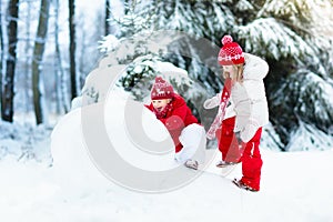 Kids building snowman. Children in snow. Winter fun.