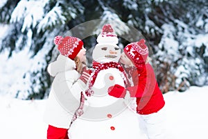 Kids building snowman. Children in snow. Winter fun.