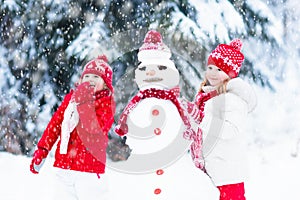 Kids building snowman. Children in snow. Winter fun.