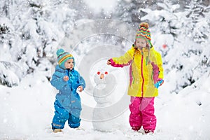 Kids building snowman. Children in snow. Winter fun