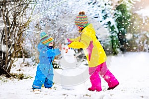 Kids building snowman. Children in snow. Winter fun.