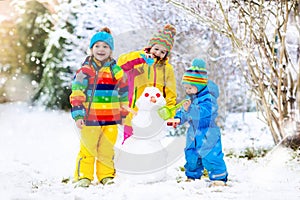 Kids building snowman. Children in snow. Winter fun.