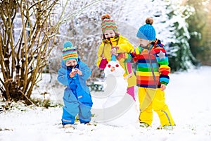 Kids building snowman. Children in snow. Winter fun.