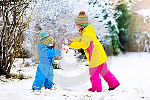 Kids building snowman. Children in snow. Winter fun.