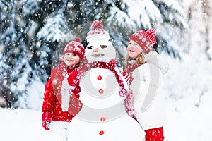 Kids building snowman. Children in snow. Winter fun.