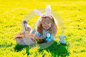 Kids in bunny ears on Easter egg hunt in garden. Children with colorful eggs in grass. Toddler boy play outdoors. Child