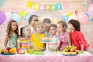 Kids celebrate birthday party and blow candles on festive cake