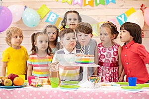 Kids celebrate birthday party and blow candles on festive cake