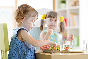 Kids children eating vegetables in kindergarten or at home