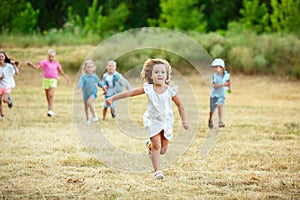 Kids, children running on meadow in summer`s sunlight