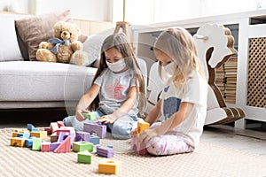 Kids children wearing mask for protect Covid-19, playing block toys in playroom.