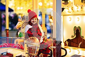 Kids at Christmas fair. Child at traditional street Xmas market in Germany. Winter outdoor fun. Little girl in knitted hat riding