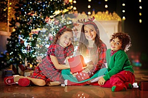 Kids at Christmas tree. Children open presents