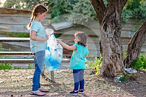 Kids cleaning in forest.Volunteer children with garbage bag cleaning up litter, putting plastic bottle in recycling bag.