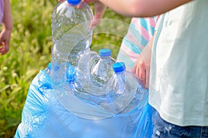 Kids cleaning in park.Volunteer children with a garbage bag cleaning up litter, putting plastic bottle in recycling bag.