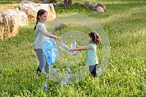 Kids cleaning in park.Volunteer children with a garbage bag cleaning up litter, putting plastic bottle in recycling bag.