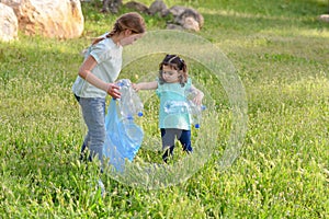 Kids cleaning in park.Volunteer children with a garbage bag cleaning up litter, putting plastic bottle in recycling bag.