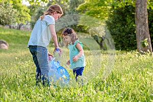 Kids cleaning in park.Volunteer children with a garbage bag cleaning up litter, putting plastic bottle in recycling bag.